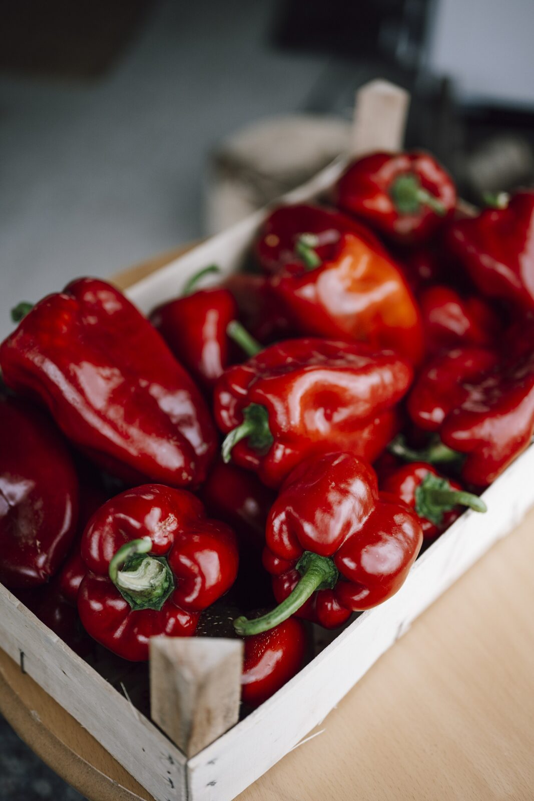 Fresh red peppers piled in a wooden crate, the variety used to make ajvar