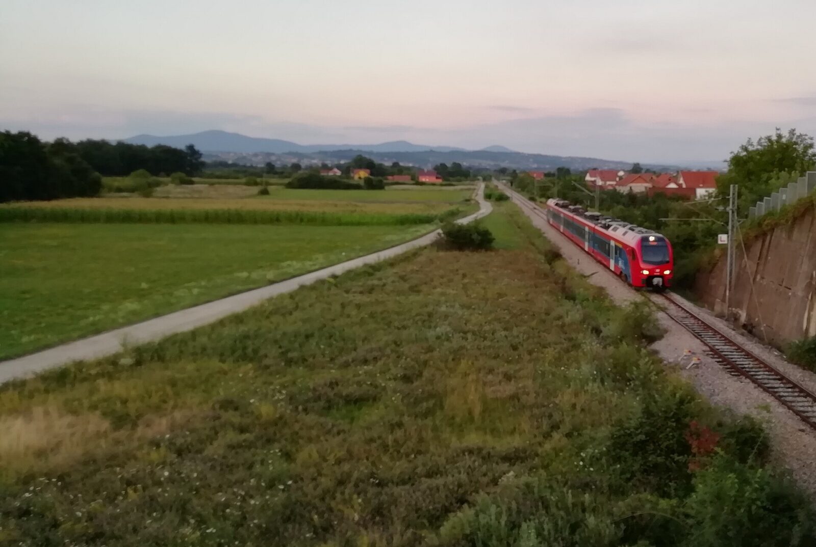 A passenger train crossing the Serbian countryside at dusk on the way south