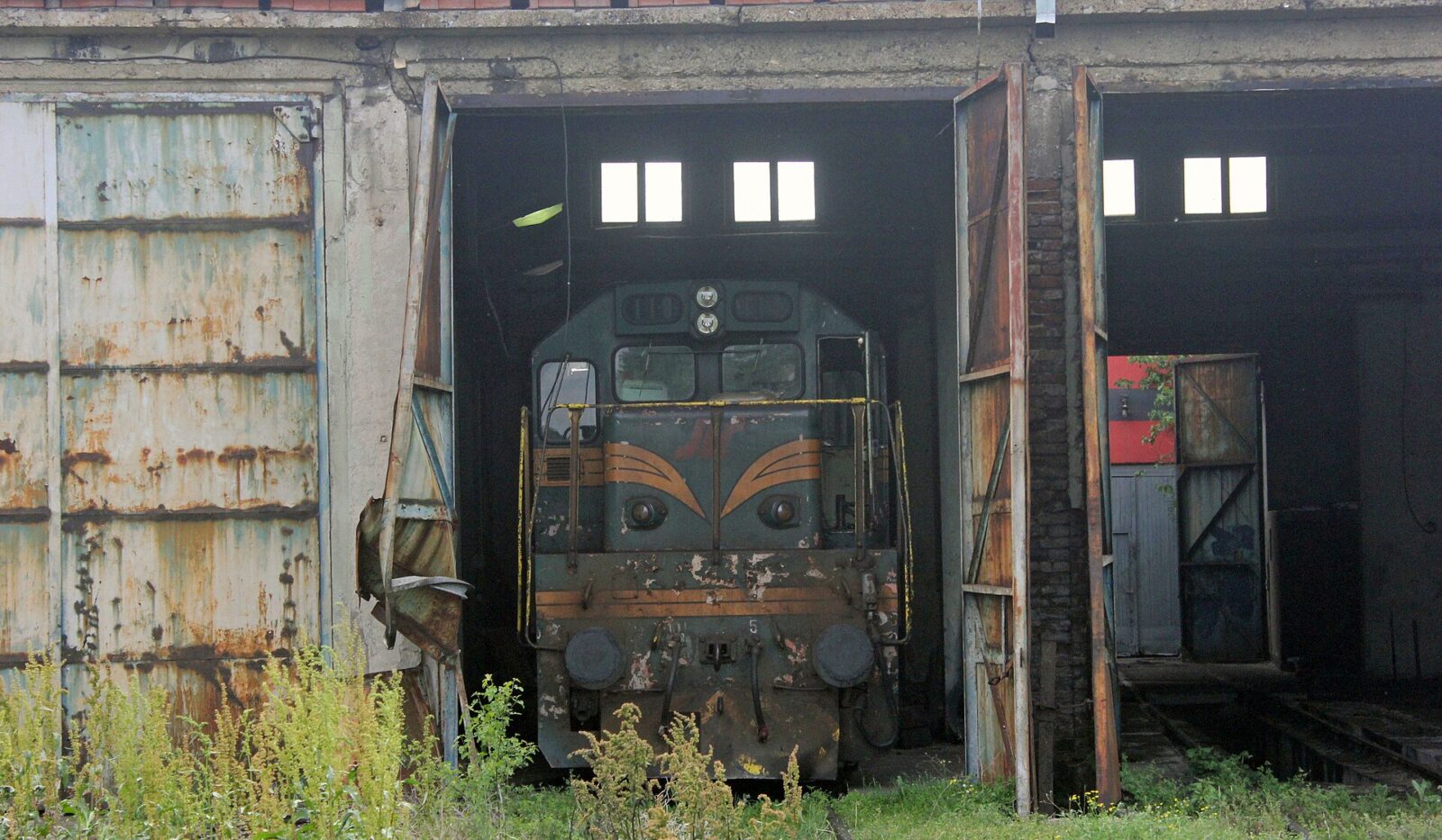 A diesel locomotive standing in the doorway of an old engine shed
