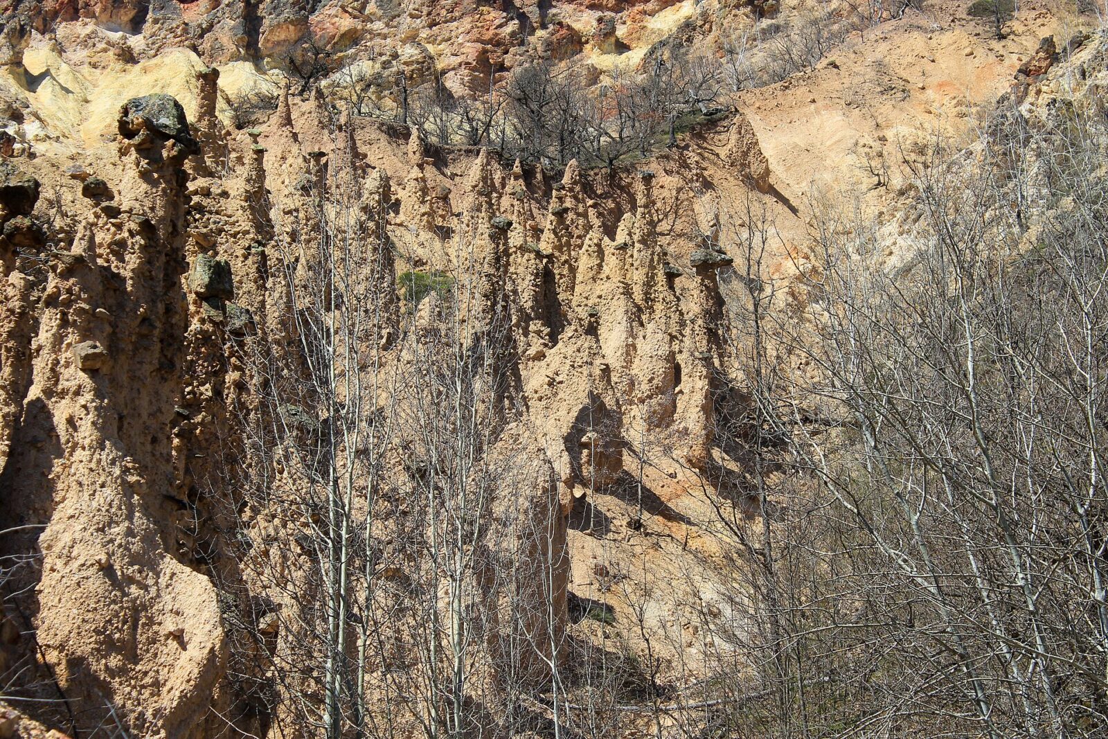 A cluster of earth pillars at Đavolja Varos, several capped by dark boulders