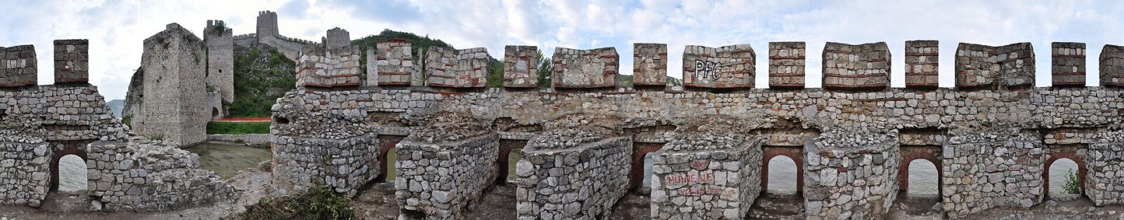 A tower of Golubac Fortress seen close up, its stonework rising above the ramparts