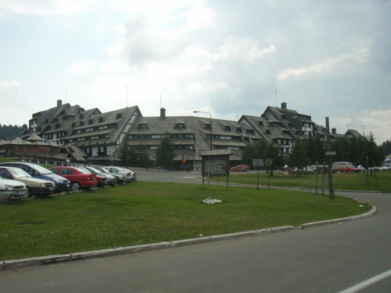Cars parked outside a chalet-style resort building at Kopaonik, with the access road alongside
