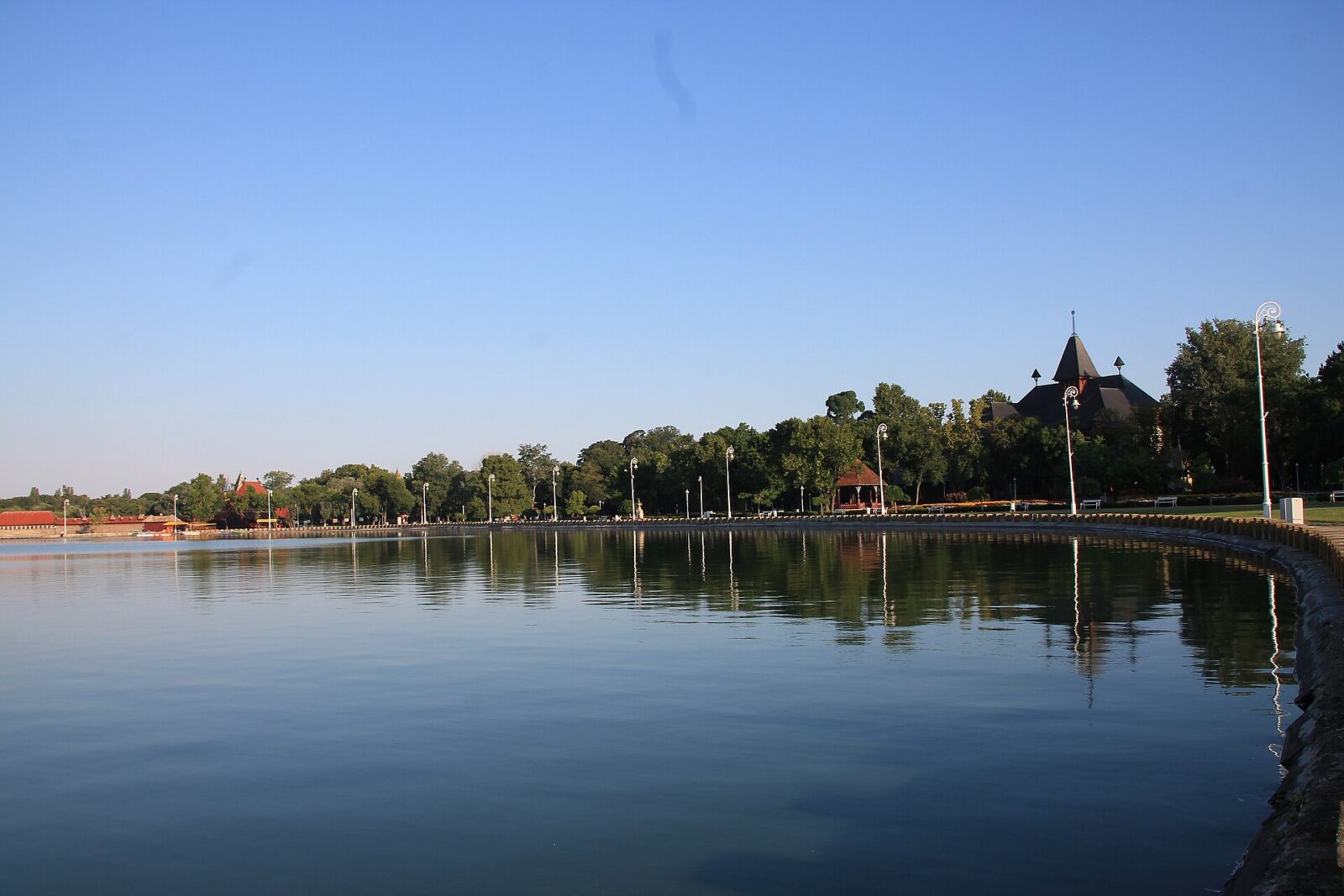Palic lake's shoreline promenade, with an Art Nouveau pavilion roof beyond the trees