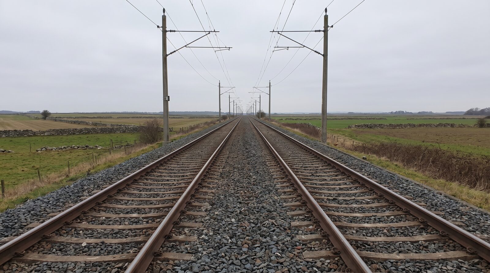 A railway track stretching through flat countryside toward the horizon