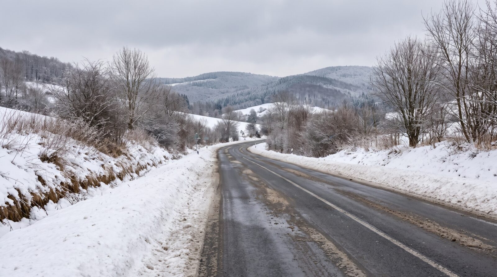 A road runs through a snow-covered mountain landscape in winter