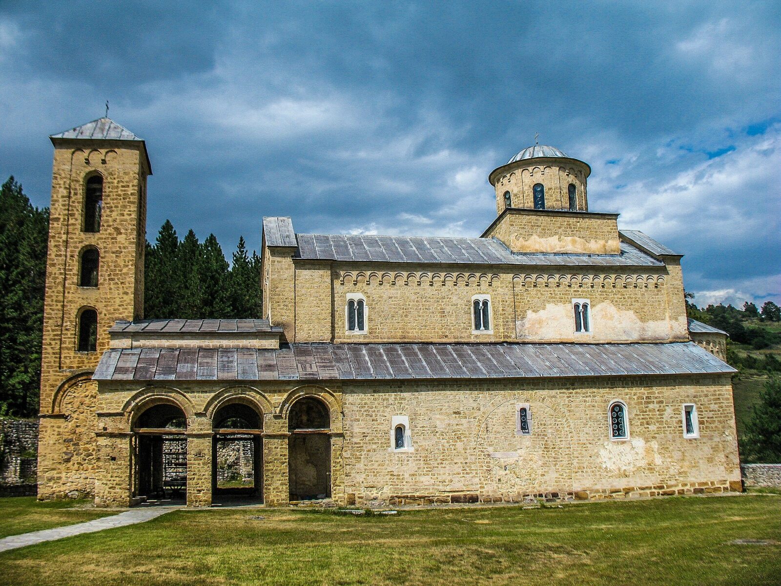 Sopocani monastery seen from the south, its bell tower and domed church under a heavily clouded sky