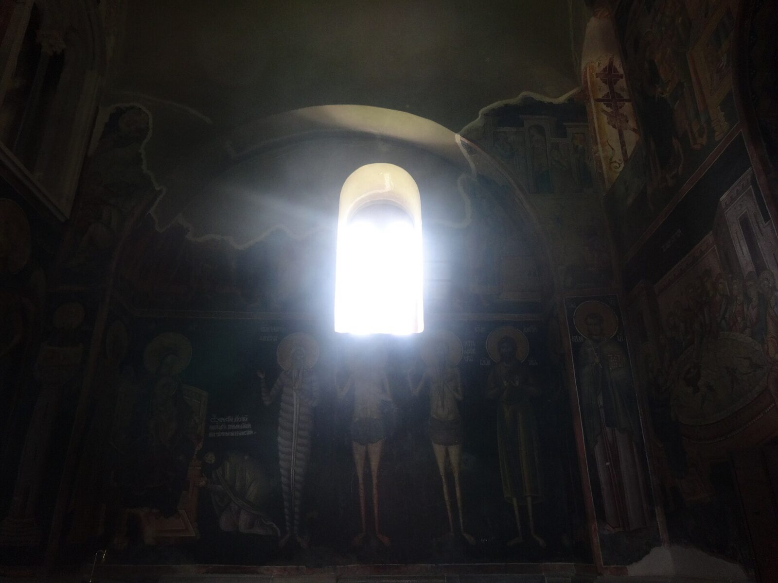 A shaft of light falling across painted frescoes inside one of Studenica's churches