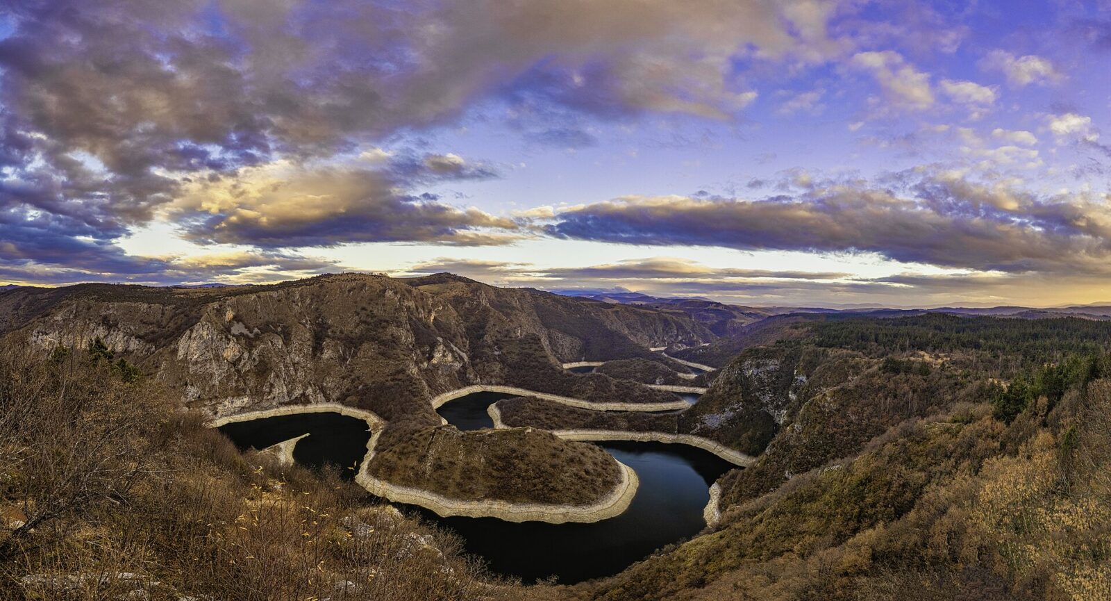 The meanders of the Uvac river seen from a clifftop viewpoint at dusk, the water looping between limestone ridges